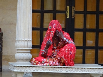 A lady sitting in the courtyard singing rajasthani folklore